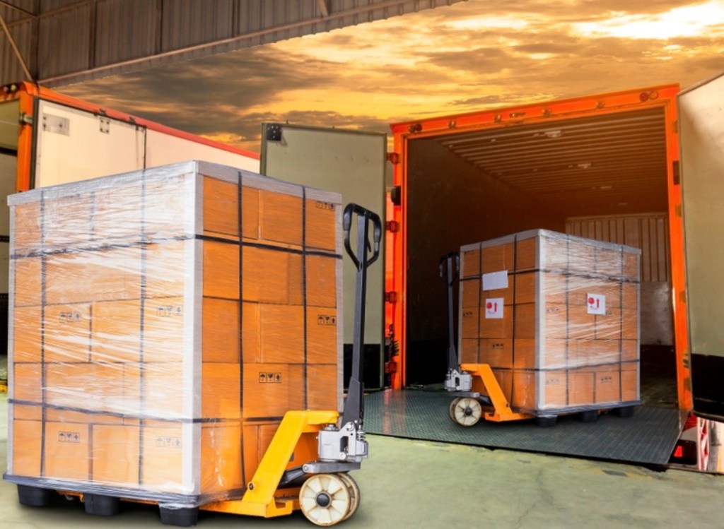 Two stack of brown cardboard packages, one on a yellow pallet trolley and the other inside an orange shipping container.